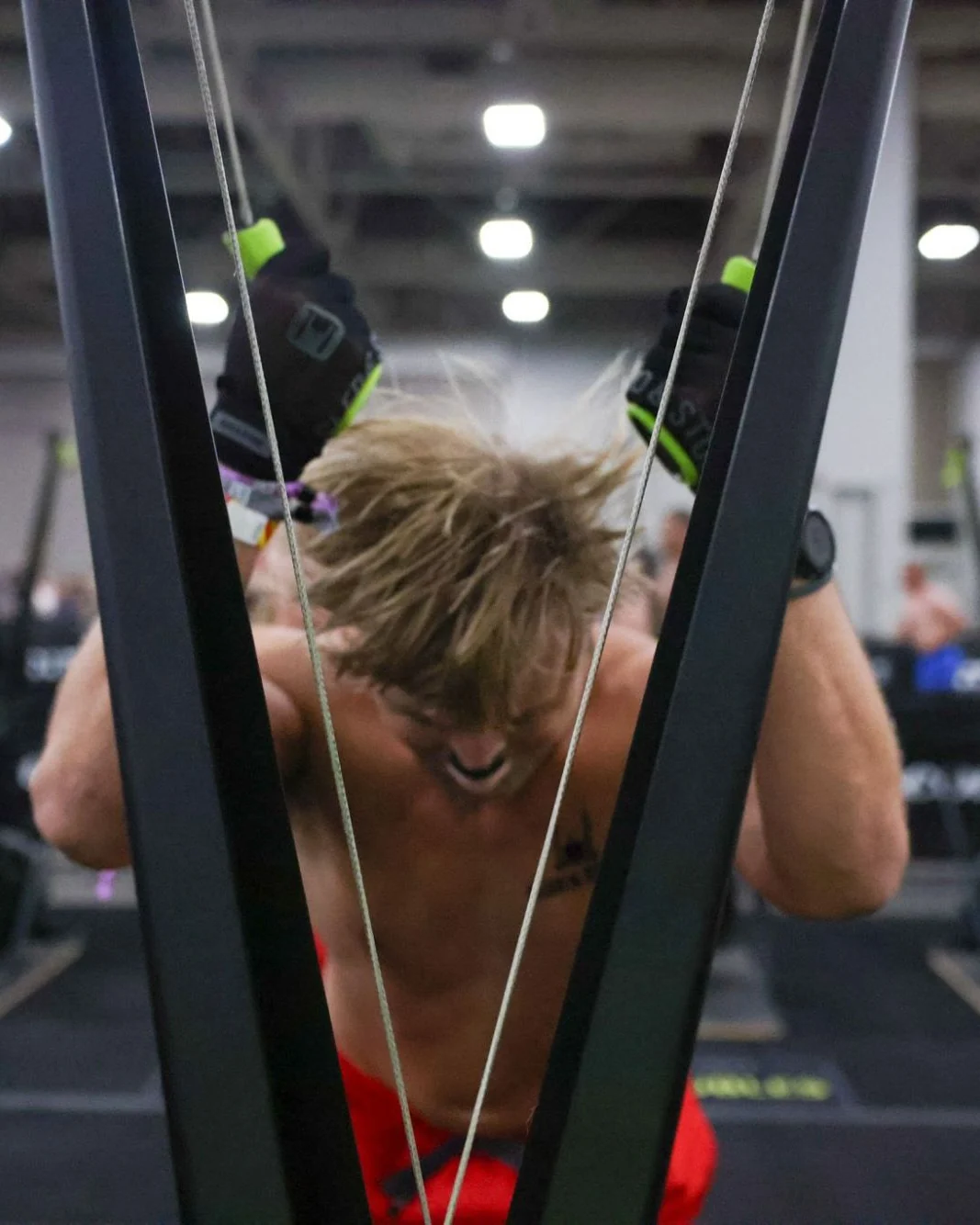 Richard Taylor on the SkiErg at HYROX Salt Lake City, a Sled & Stone glove on each handle