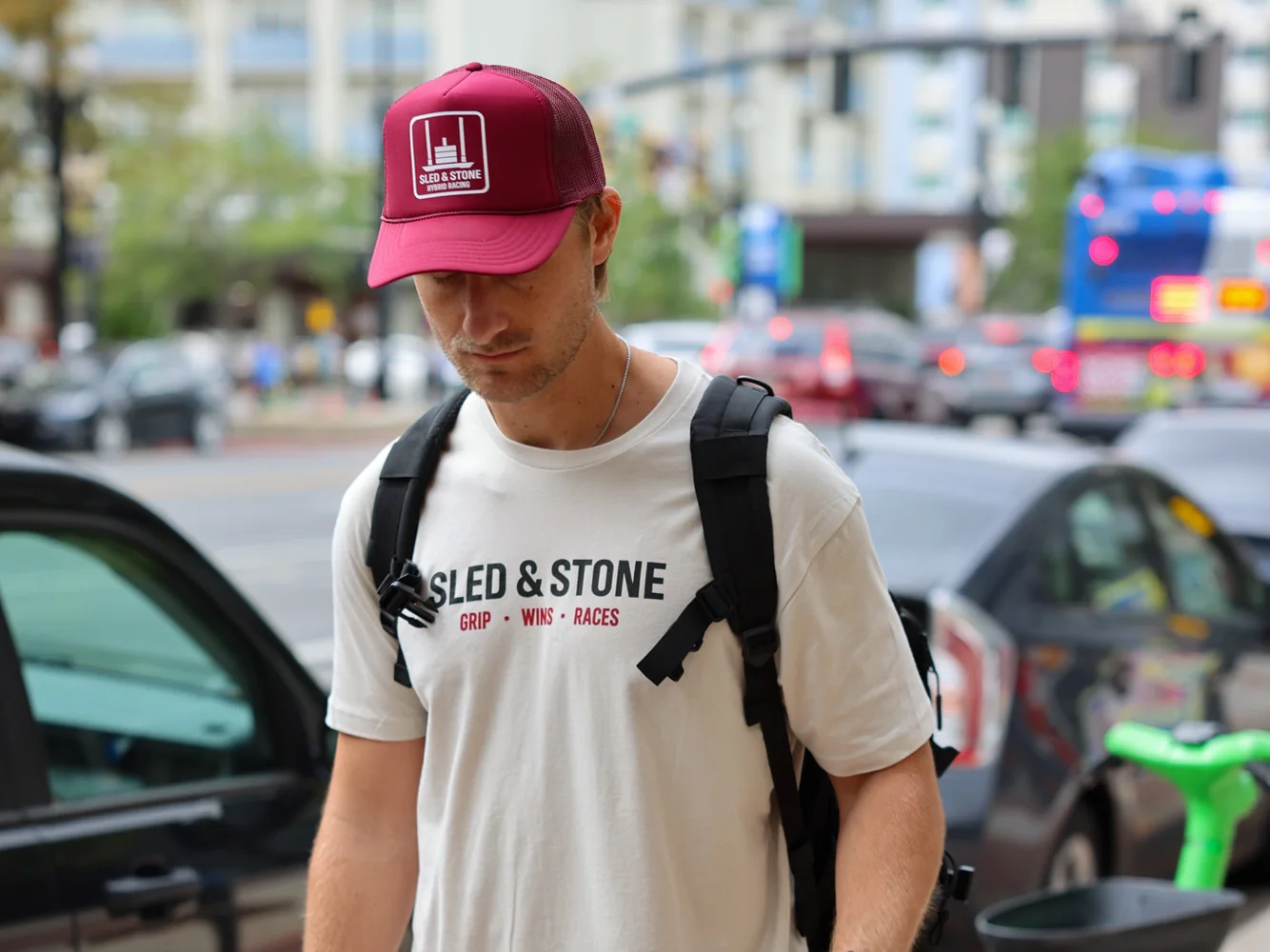 The red Hybrid Racing trucker, laid on turf, with the white Sled & Stone Hybrid Racing patch on the front — view 2