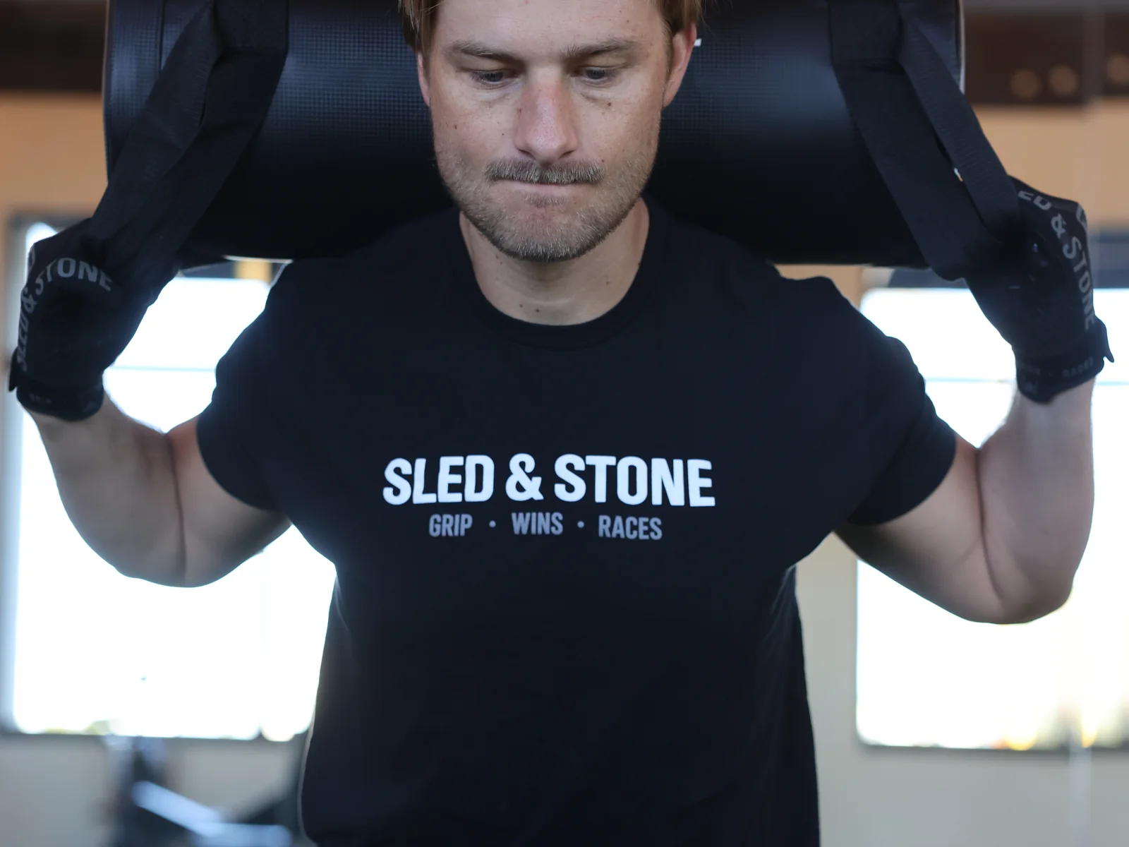 The Grip Wins Races tee in black and sand, worn side by side: Sled & Stone across the chest over Grip Wins Races — view 6